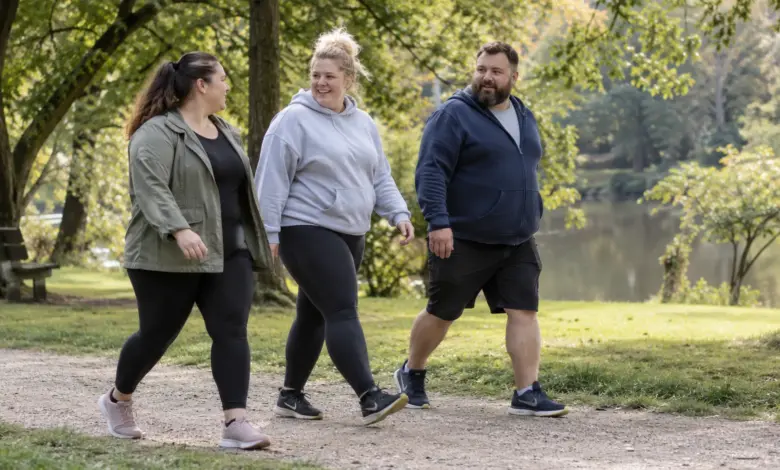 Drei Erwachsene mit unterschiedlichen Körperformen gehen im Park spazieren [Bildinhalt mit KI erstellt]