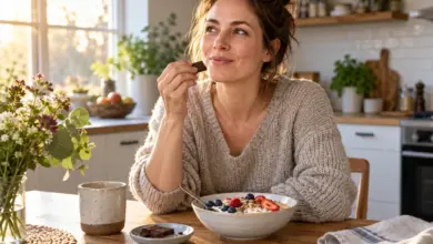 Frau genießt ein Stück Schokolade am Küchentisch neben Joghurt mit Haferflocken und Beeren. [Bildinhalt mit KI erstellt]